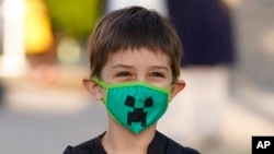 ARHIVA - Dečak nosi zaštitnu masku dok pozira svojoj majci za fotografiju, u Solt Lejk Sitiju, u Juti (Foto: AP/Rick Bowmer)
