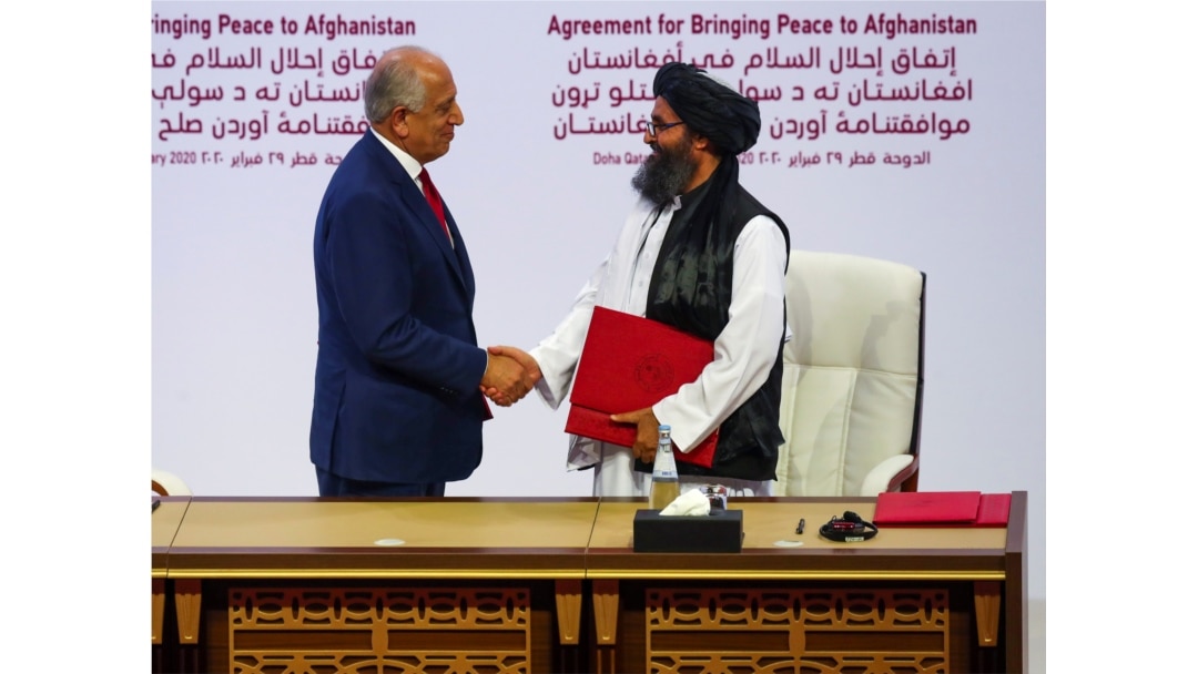 FILE - Mullah Abdul Ghani Baradar, leader of the Taliban delegation, and Zalmay Khalilzad, U.S. envoy for peace in Afghanistan, shake hands after signing an agreement between Afghanistan's Taliban and the U.S. in Doha, Qatar, Feb. 29, 2020.