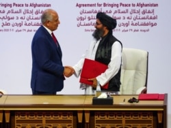 Mullah Abdul Ghani Baradar, the leader of the Taliban delegation, and Zalmay Khalilzad, U.S. envoy for peace in Afghanistan, shake hands after signing an agreement in Doha, Qatar, Feb. 29, 2020.