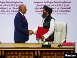 FILE - Mullah Abdul Ghani Baradar, the leader of the Taliban delegation, and Zalmay Khalilzad, U.S. envoy for peace in Afghanistan, shake hands after signing an agreement between Afghanistan's Taliban and the U.S. in Doha, Qatar, Feb. 29, 2020.