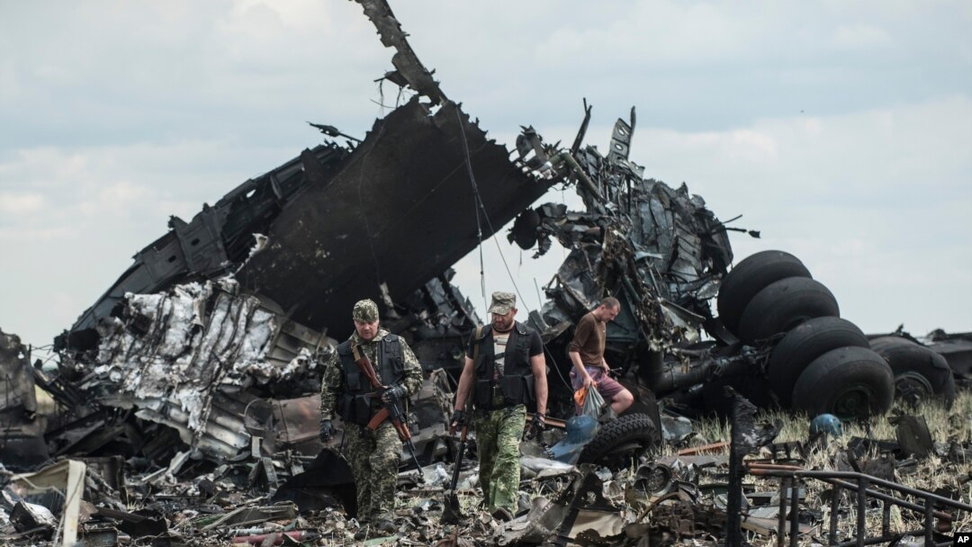 Pro-Russian fighters collect ammunition from the site of remnants of a downed Ukrainian army aircraft Il-76 at the airport near Luhansk, Ukraine, Saturday, June 14, 2014. 