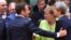 French President Emmanuel Macron (left) puts his hand on the shoulder of British Prime Minister Theresa May during a round table meeting at an EU summit in Brussels, June 22, 2017. German Chancellor Angela Merkel stands between them.