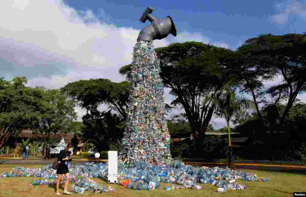 A delegate looks at a 30-foot monument dubbed &quot;turn off the plastic tap&quot; by Canadian activist and artist Benjamin von Wong, made with plastic waste collected from Kibera slums, at the venue of the Fifth Session of the United Nations Environment Assembly at the U.N. Environment Program Headquarters in Gigiri, Nairobi, Kenya.