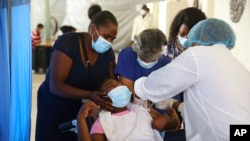 Un trabajador de la salud administra a un joven una inyección de la vacuna Moderna contra COVID-19 en el Hospital Saint Damien en Puerto Príncipe, Haití, el martes 27 de julio de 2021.
