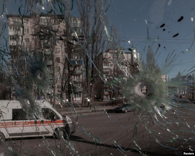 Ambulans terlihat melalui jendela rusak kendaraan yang terkena peluru, saat invasi Rusia ke Ukraina berlanjut, di Kyiv, Ukraina, 28 Februari 2022. (Foto: via Reuters)