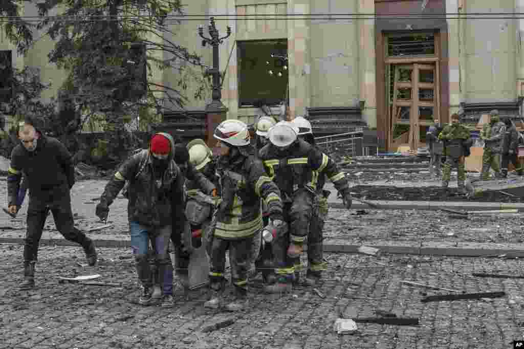 Ukrainian emergency service personnel carry a body of a victim out of the damaged City Hall building following shelling in Kharkiv, March 1, 2022.