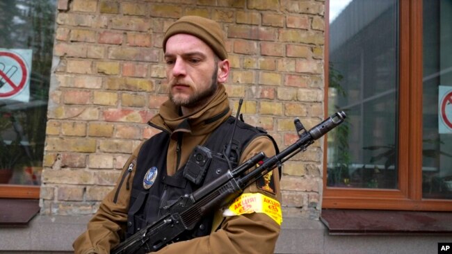 An armed civil defense man holds a Kalashnikov assault rifle while patrolling an empty street due to curfew in Kyiv, Ukraine, Feb. 27, 2022.