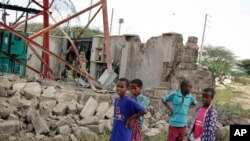 Children look at a damaged telecommunications mast after an attack by al-Shabab extremists from Somalia, in a Kenyan settlement, Jan. 13, 2020.
