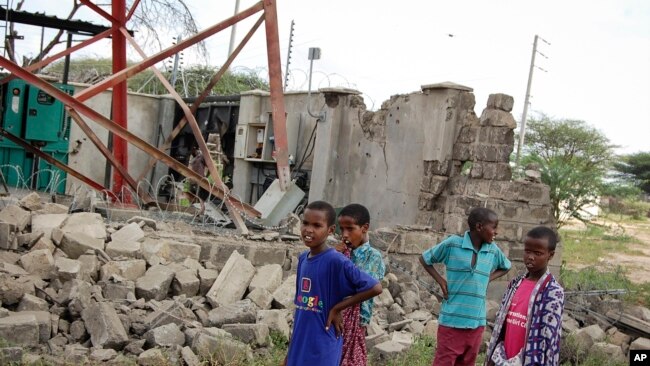 Anak-anak memperhatikan menara telekomunikasi yang rusak akibat serangan extremis al-Shabab dari Somalia, di sebuah permukiman Kenya, 13 Januari 2020. (Foto: Associated Press)