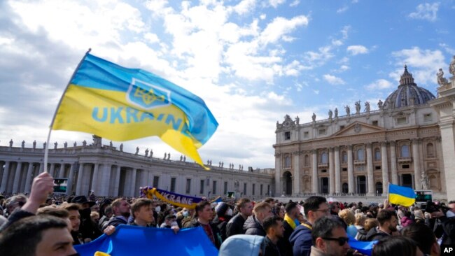 Besimtarët shfaqin flamujt ukrainas gjatë lutjes së mesditës të Papa Françeskut në sheshin e Shën Pjetrit në Vatikan, të dielën, 27 shkurt 2022. (AP Photo/Gregorio Borgia)