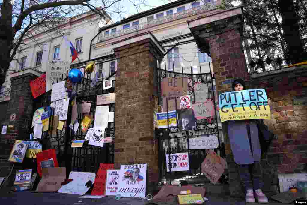 A woman holds a sign as she stands next to placards placed by people to protest against Russia&#39;s massive military operation in Ukraine, at the Russian Embassy in London, Feb. 27, 2022.