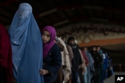 FILE - Women queue to receive cash at a money distribution site organized by the World Food Program in Kabul, Afghanistan, Nov. 20, 2021.