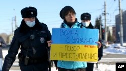 Police detain a demonstrator with a poster which reads "The war with Ukraine is a shame and a crime" during an action against Russia's attack on Ukraine in Omsk, Russia, Feb. 27, 2022.