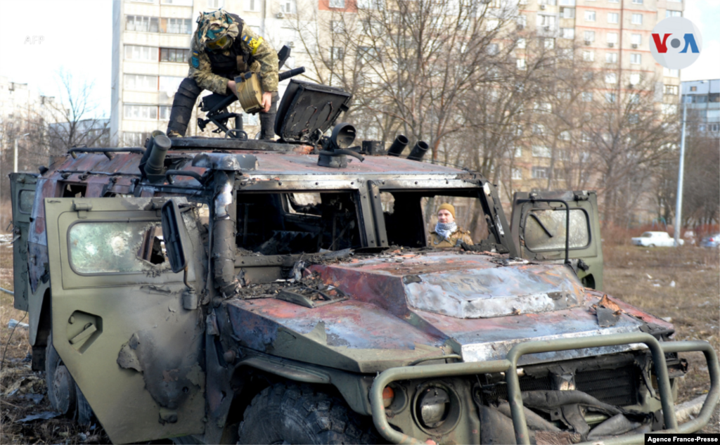 Un combatiente de defensa territorial de Ucrania examina un vehículo ruso que fue destruido después de un enfrentamiento en Kiev.