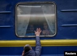 Children look out from an evacuation train from Kyiv to Lviv as they say goodbye to their father at Kyiv central train station in central Kyiv, Ukraine, March 3, 2022.
