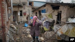 Una mujer luce abrumada en el patio trasero de una casa dañada por un ataque aéreo ruso, según lugareños, en Gorenka, en las afueras de Kiev, Ucrania, el 2 de marzo de 2022.