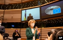 La presidenta de la Comisión Euopea, Ursula von der Leyen, y otros legisladores europeos aplauden de pie al presidente ucraniano Volodymyr Zelenskyy después de un discurso por video para pedir la admisión de Ucrania en la Unión Europea el 1 de marzo de 2022.