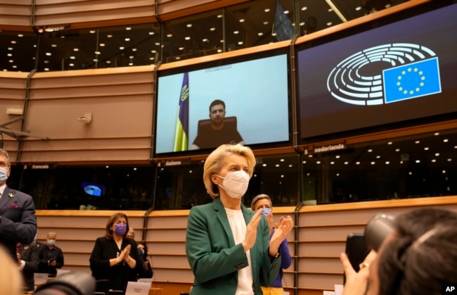 La presidenta de la Comisión Euopea, Ursula von der Leyen, y otros legisladores europeos aplauden de pie al presidente ucraniano Volodymyr Zelenskyy después de un discurso por video para pedir la admisión de Ucrania en la Unión Europea el 1 de marzo de 2022.