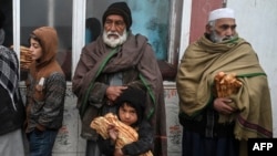 FILE - Recipients of free bread, distributed as part of a campaign to combat hunger, are pictured in front of a bakery in Kabul, Afghanistan, Jan. 18, 2022.