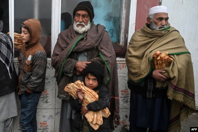 FILE - Recipients of free bread, distributed as part of a campaign to combat hunger, are pictured in front of a bakery in Kabul, Afghanistan, Jan. 18, 2022.