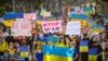 Ukrainians carried signs opposing to war and Russia President Vladimir Putin during a street march in Bangkok after Russia's invasion of Ukraine, Bangkok, Thailand, Feb.27, 2022 (Tommy Walker/VOA)