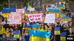 Ukrainians carried signs opposing to war and Russia President Vladimir Putin during a street march in Bangkok after Russia's invasion of Ukraine, Bangkok, Thailand, Feb.27, 2022 (Tommy Walker/VOA)