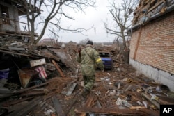 Andrey Goncharuk, 68, a member of territorial defense, walks in the backyard of a house damaged by a Russian airstrike, according to locals, in Gorenka, outside the capital Kyiv, Ukraine, March 2, 2022.