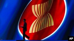 FILE - A steward walks past the ASEAN logo during the ASEAN Business and Investment Summit, a parallel event to the ASEAN summit, in Nonthaburi, Thailand, Nov. 2, 2019.