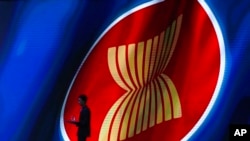FILE - A steward walks past the ASEAN logo during the ASEAN Business and Investment Summit, a parallel event to the ASEAN summit, in Nonthaburi, Thailand, Nov. 2, 2019.