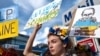 Seorang perempuan Ukraina mengacungkan poster dalam demo memprotes invasi Rusia ke Ukraina, di Los Angeles, AS, Sabtu, 26 Februari 2022. (Foto: Richard Voge/AP)