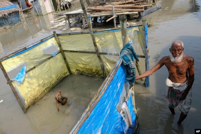 FILE - An elderly man stands by a tube well buried in water during high tide in Pratap Nagar, in Shyamnagar region of Satkhira district, Bangladesh on Oct. 5, 2021. (AP Photo/Mahmud Hossain Opu, File)