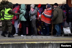 People wait on a platform after arriving with a Ukrainian train transporting hundreds of people fleeing from the Russian invasion, at the train station in Przemysl, Poland, Feb. 28, 2022.