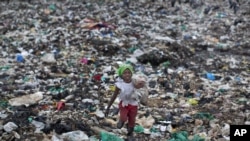 FILE - Joyce Njeri, 8, walks with a torn sack carrying the plastic bottles she has scavenged, at the garbage dump in the Dandora slum of Nairobi, Kenya.