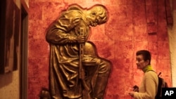 A tourist from Britain stands in front of a relief of a kneeing red army soldier during celebrations of Victory Day at the German-Russian Museum in Berlin, Germany, May 8, 2014