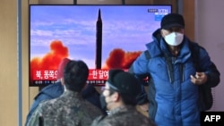FILE - People watch a television screen showing a news broadcast with file footage of a North Korean missile test, at a railway station in Seoul, South Korea, on Feb. 27, 2022, 