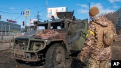 A Ukrainian soldier inspects a damaged military vehicle after fighting in Kharkiv, Feb. 27, 2022. 