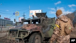 Ukrayna hərbi qüvvələrinin əsgəri Xarkovda döyüşdən sonra zədələnmiş hərbi maşını yoxlayır, 27 fevral 2022-ci il.