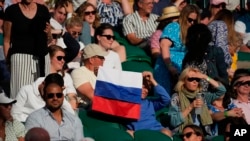 FILE - A spectator holds up a Russian flag as he watches a men's singles match on between Russia and Croatia at the Wimbledon Tennis Championships in London, July 3, 2021.