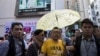 FILE - Pro-democracy activist Tam Tak-chi, center, is escorted away by police after confronting government supporters in Hong Kong, April 25, 2015.