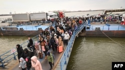 FILE - People coming from Ukraine board a ferry to Romania after crossing the Danube at the Isaccea-Orlivka border crossing between Romania and Ukraine on February 26, 2022.