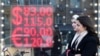 资料照片：俄罗斯妇女走过莫斯科市中心窗口显示美元与欧元兑换率的外币兑换处。（2022年2月28日）