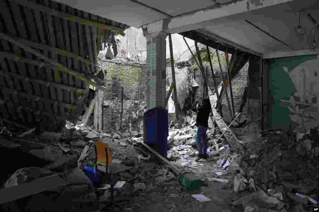 A woman takes photos of a destroyed building near a checkpoint in Brovary, outside Kyiv, March 1, 2022.