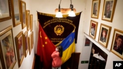 A visitor to a Ukrainian restaurant holds Chinese and Ukraine flags as she poses for a photo, Feb. 24, 2022, in Beijing. China’s customs agency on Thursday approved imports of wheat from Russia, a move that could help to reduce the impact of Western sanctions imposed over Moscow’s attack on Ukraine.