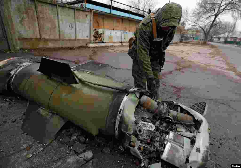 A militant of the self-proclaimed Donetsk People&#39;s Republic inspects the remains of a missile that landed on a street in the separatist-controlled city of Donetsk, Ukraine Feb. 26. 2022.