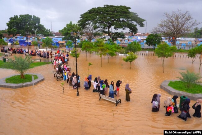 Warga mengarungi banjir saat mengungsi pasca banjir di Serang, Provinsi Banten, 1 Maret 2022. (Foto: AFP/Dziki Oktomauliyadi)