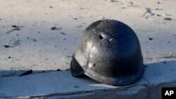 被丟棄在路邊的鋼盔，上面的彈孔清晰可見。