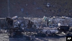 Militares ucranianos inspeccionan el sitio de un ataque aéreo ruso en Kiev, Ucrania, el sábado 26 de febrero de 2022. (Foto AP/Vadim Ghirda)