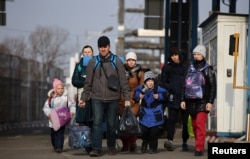 A group of people walk after fleeing from Russia's invasion of Ukraine, at the border crossing in Sighetu Marmatiei, Romania, March 3, 2022.