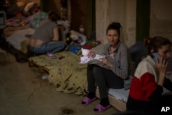 A woman holds her newborn baby at a basement used as a bomb shelter at the Okhmadet children's hospital in central Kyiv, Ukraine, Feb. 28, 2022. (AP Photo/Emilio Morenatti)