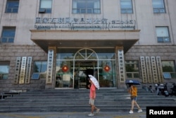 FILE - People walk past an office of the Cyberspace Administration of China (CAC) in Beijing, China, July 8, 2021.